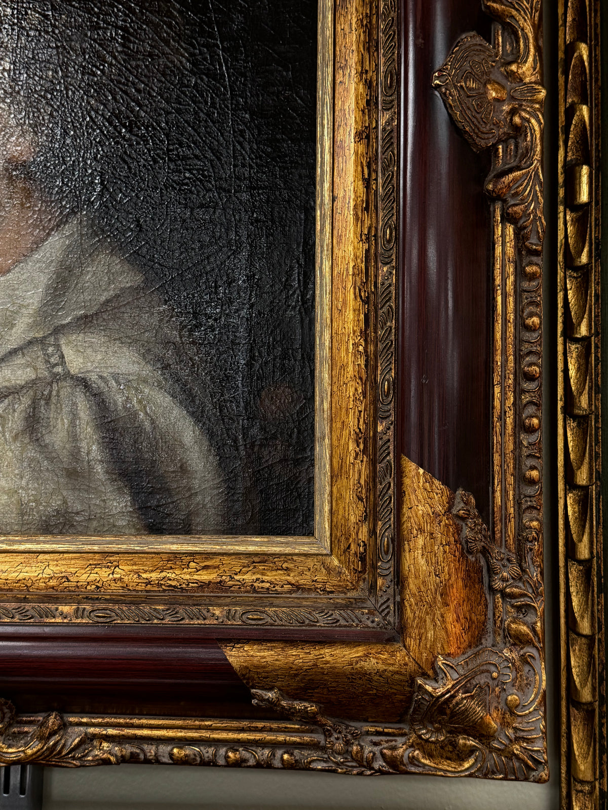 Detail of craquelure in the dark background and the ornate frame corner